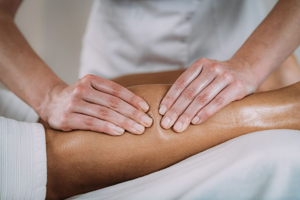 Professional lymphatic drainage treatment on a patient's leg, while massaging oily skin.