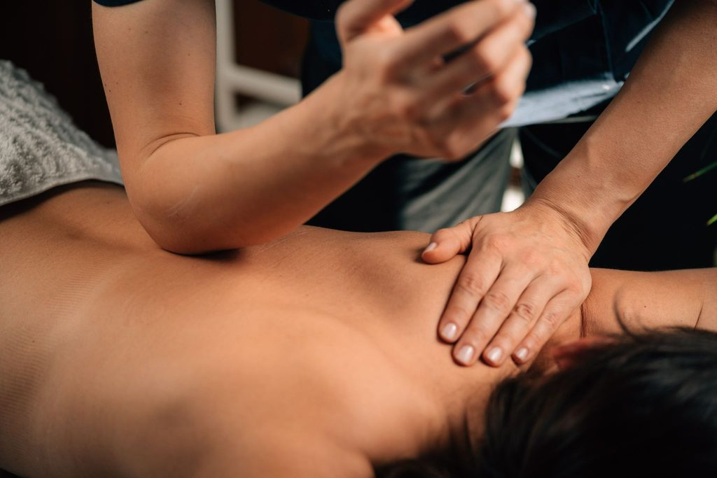 A masseuse performs chiropractic treatment on a man's back.